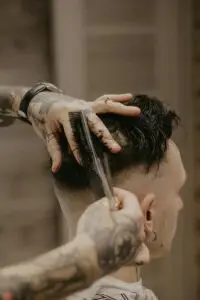 stock image of a barber combing through a clients hair as he cuts it